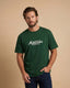 Man wearing a green t-shirt with 'Montavor Western Wear' logo against a beige background