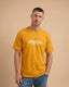 Man wearing a mustard yellow t-shirt with 'Montavor Western Wear' logo on a beige background