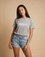 Woman wearing a gray t-shirt with 'Montavor' text and denim shorts on a beige background