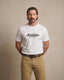 Man wearing a white t-shirt with 'Mon Western Wear' text against a beige backgroundavor