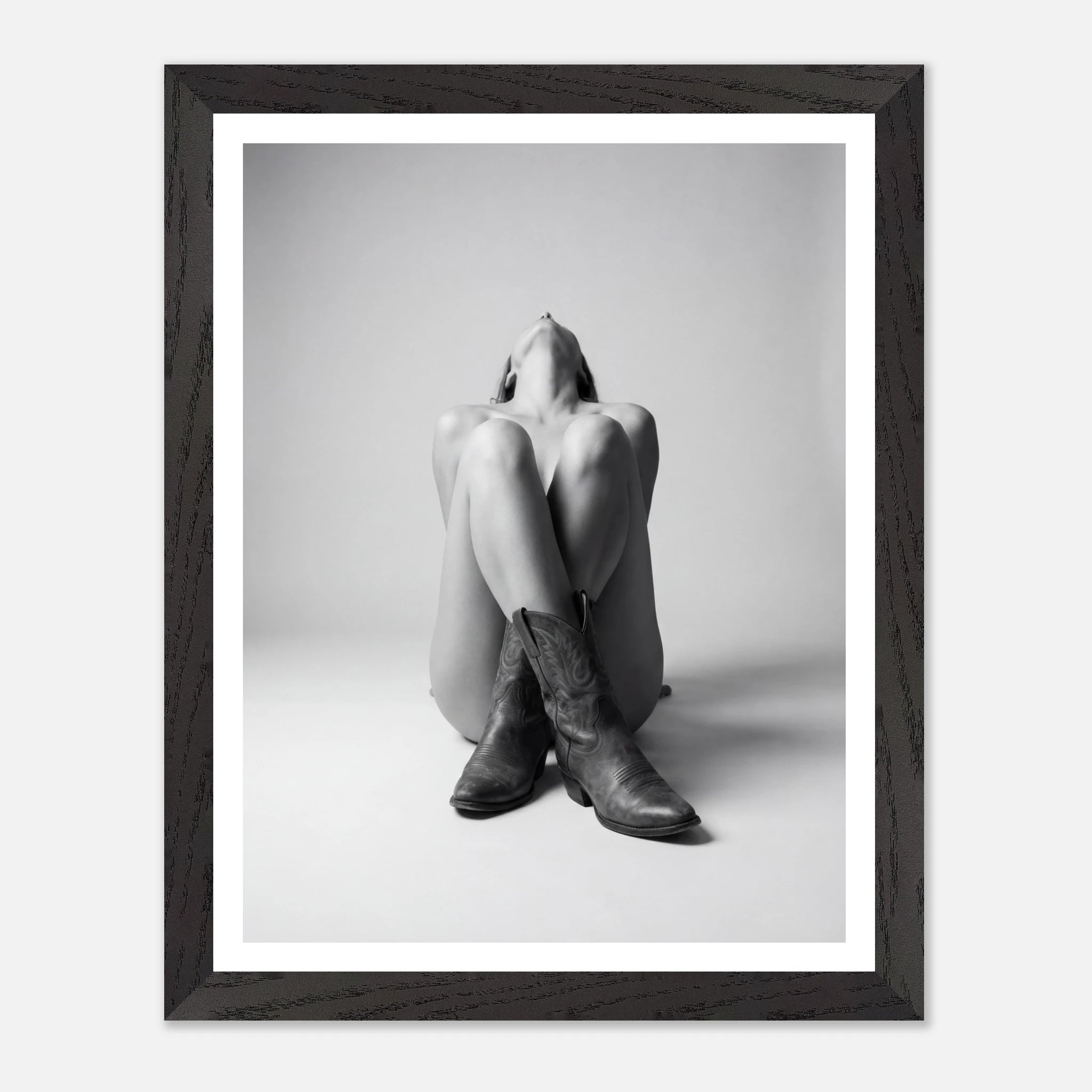 Framed black and white photo of a person wearing cowboy boots on a light gray background
