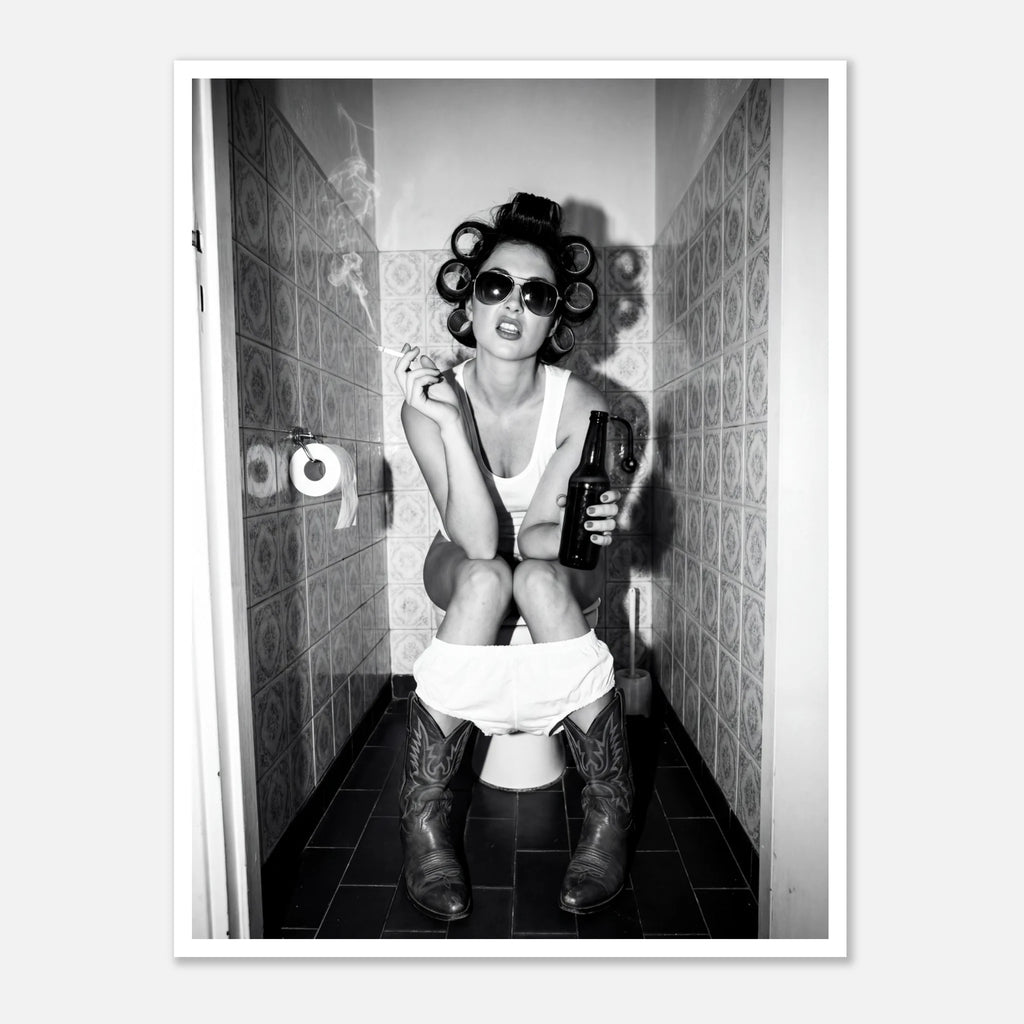 Black and white photograph of a rebellious cowgirl wearing cowboy boots and sunglasses sitting in a tiled restroom holding a cigarette and beer.
