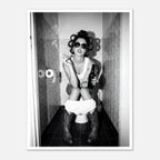 Black and white photograph of a rebellious cowgirl wearing cowboy boots and sunglasses sitting in a tiled restroom holding a cigarette and beer.