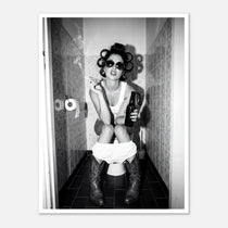 Black and white photograph of a rebellious cowgirl wearing cowboy boots and sunglasses sitting in a tiled restroom holding a cigarette and beer.