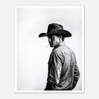 Black and white photograph of a rodeo cowboy wearing a western hat and cigarette, turning toward the camera after competition, western cowboy wall art poster.