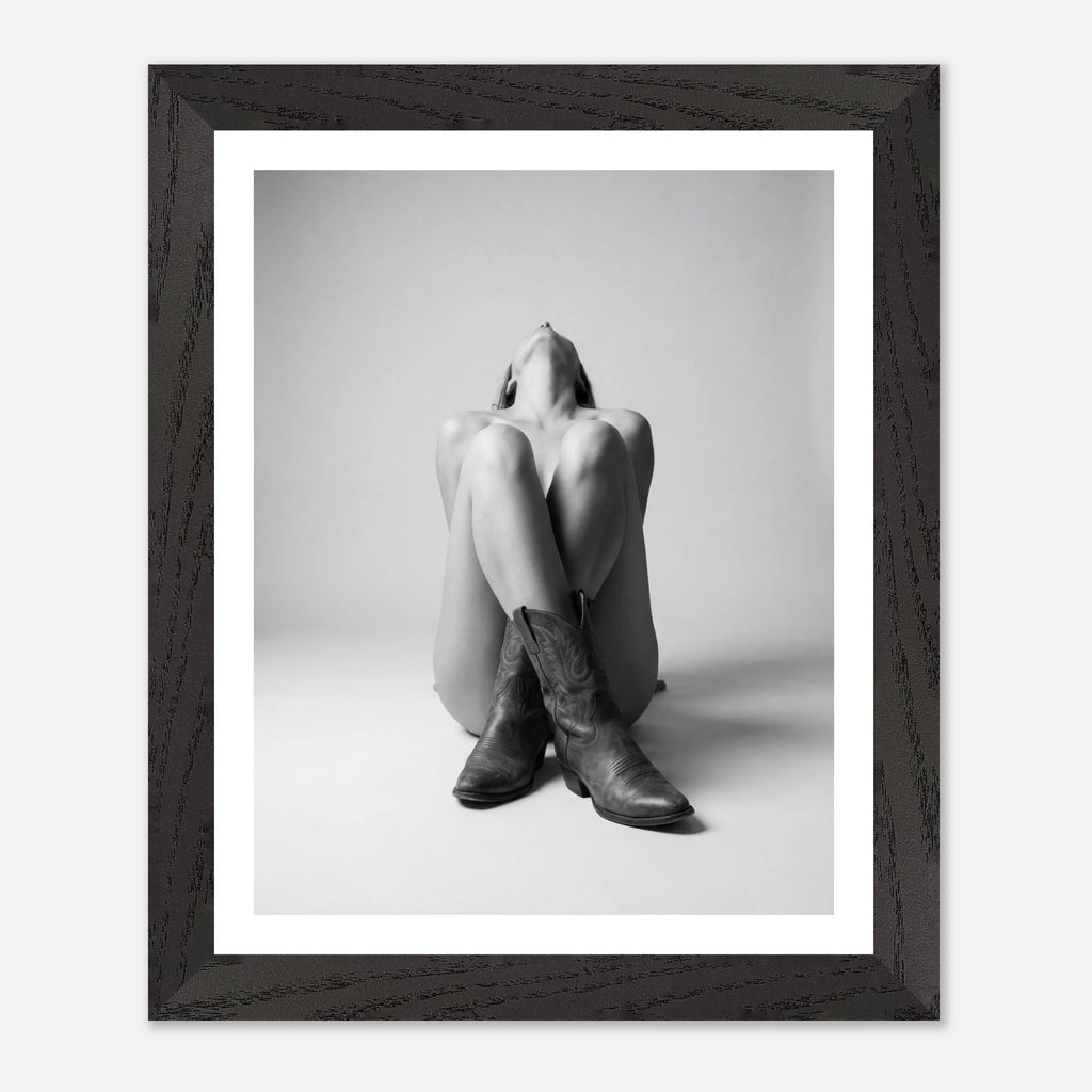 Framed black and white photo of a person wearing cowboy boots on a light background