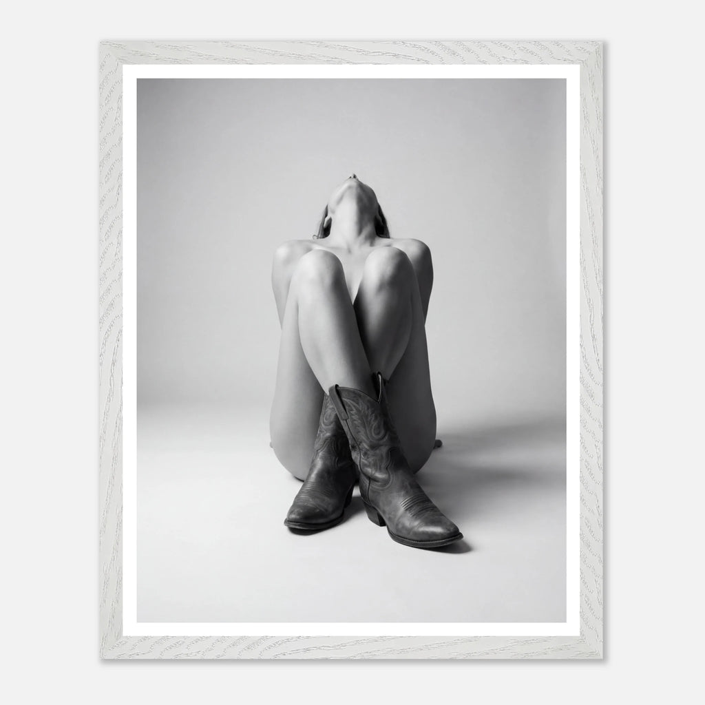 Person wearing cowboy boots sitting on a white background with a white frame.