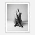 Person wearing cowboy boots sitting on a white background with a white frame.