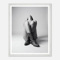 Person wearing cowboy boots sitting on a white background with a white frame.