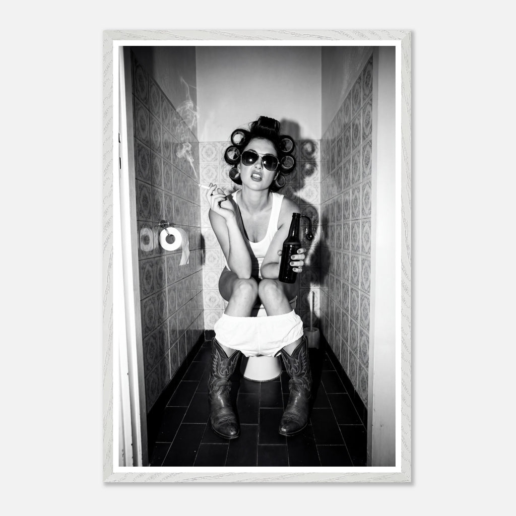 Black and white photograph of a rebellious cowgirl wearing cowboy boots and sunglasses sitting in a tiled restroom holding a cigarette and beer.