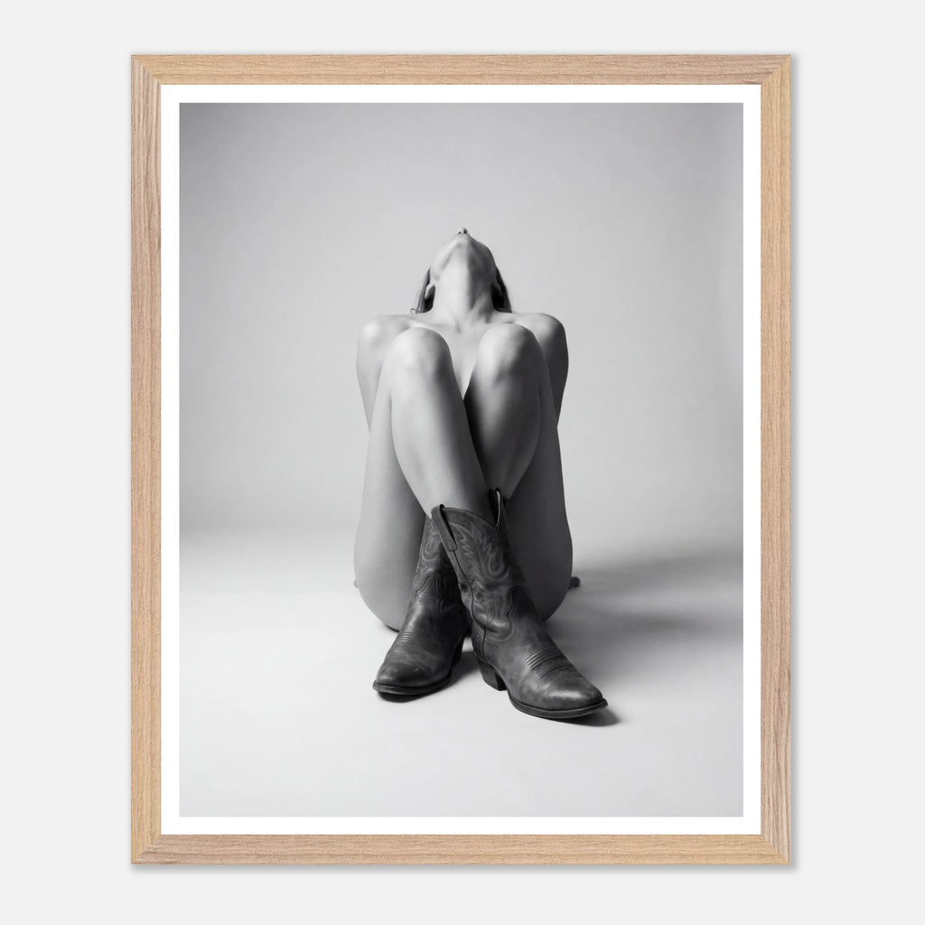 Framed black and white photo of a person wearing cowboy boots sitting on the floor.
