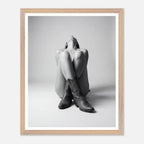 Framed black and white photo of a person wearing cowboy boots sitting on the floor.