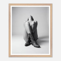 Framed black and white photo of a person wearing cowboy boots sitting on the floor.