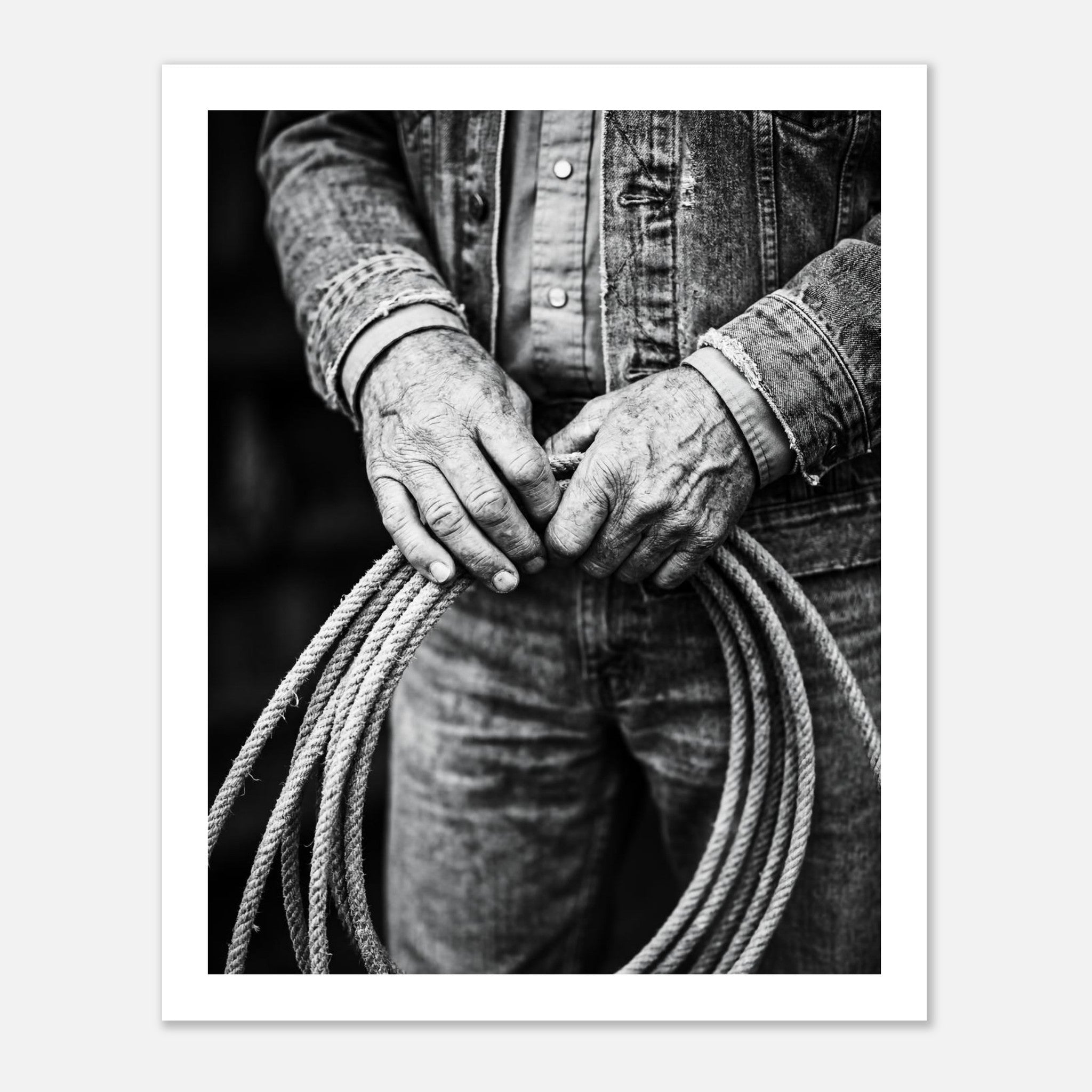 Black and white photograph of cowboy hands holding a coiled rope wearing denim, western ranch wall art.