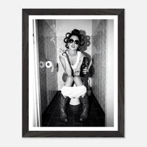 Black and white photograph of a rebellious cowgirl wearing cowboy boots and sunglasses sitting in a tiled restroom holding a cigarette and beer.