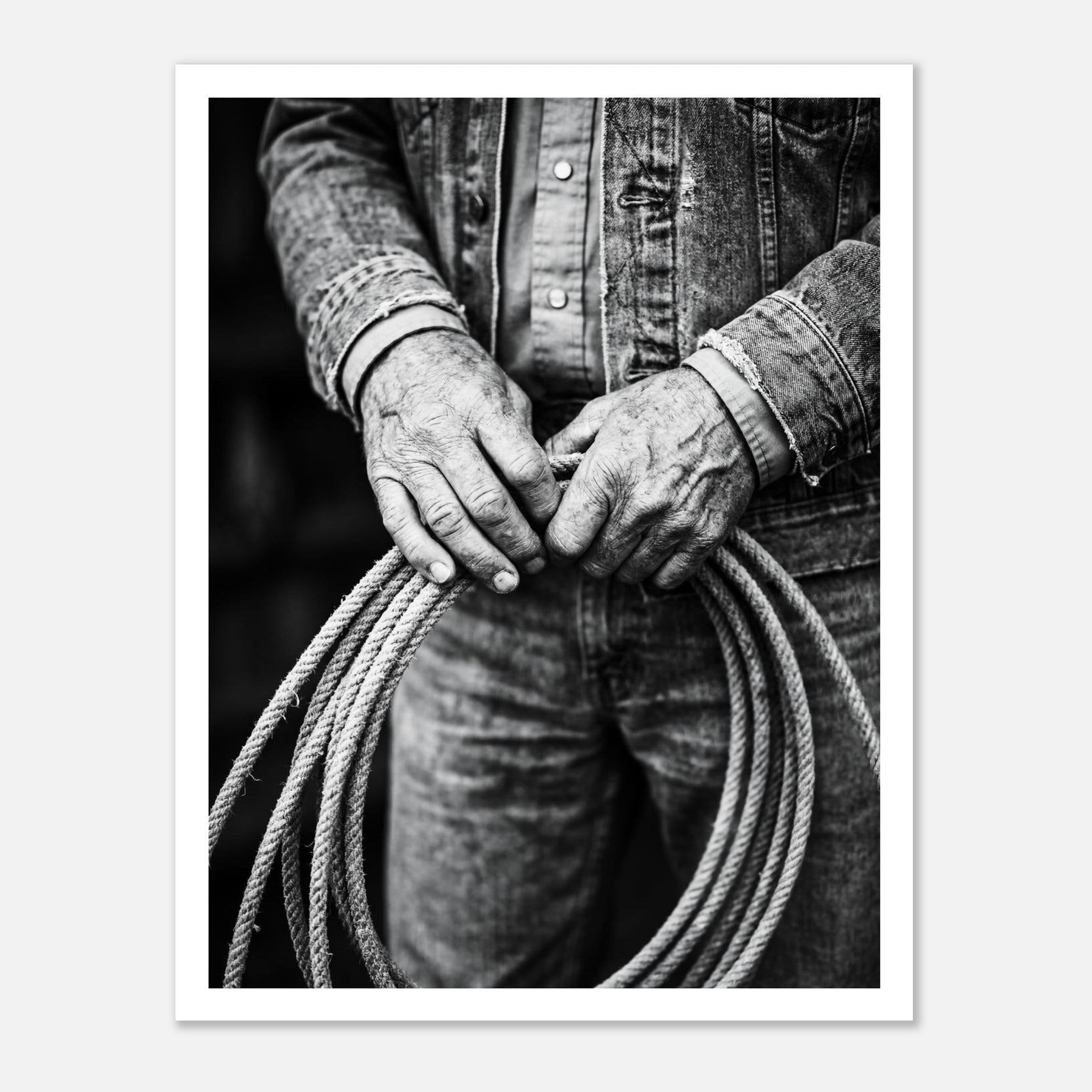 Black and white photograph of cowboy hands holding a coiled rope wearing denim, western ranch wall art.