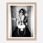 Black and white photograph of a rebellious cowgirl wearing cowboy boots and sunglasses sitting in a tiled restroom holding a cigarette and beer.