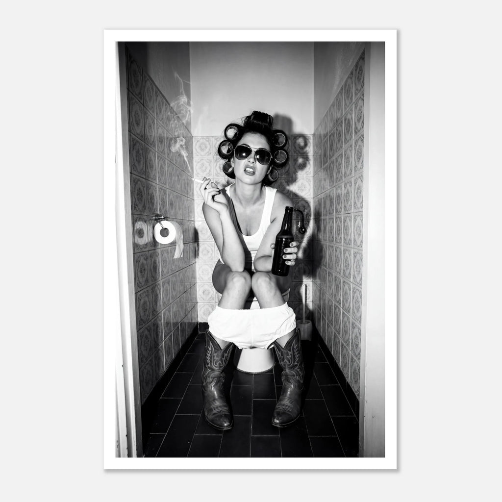 Black and white photograph of a rebellious cowgirl wearing cowboy boots and sunglasses sitting in a tiled restroom holding a cigarette and beer.