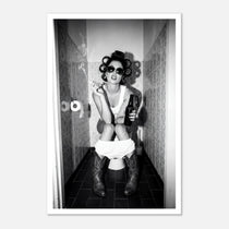 Black and white photograph of a rebellious cowgirl wearing cowboy boots and sunglasses sitting in a tiled restroom holding a cigarette and beer.