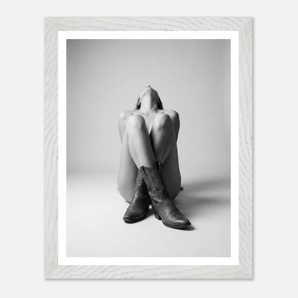 Framed black and white photo of a person wearing cowboy boots sitting on the floor.