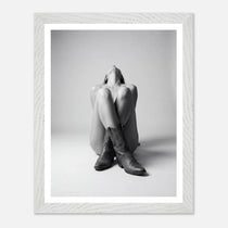 Framed black and white photo of a person wearing cowboy boots sitting on the floor.