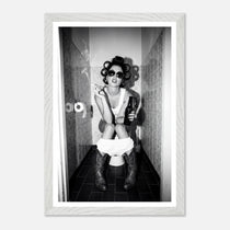 Black and white photograph of a rebellious cowgirl wearing cowboy boots and sunglasses sitting in a tiled restroom holding a cigarette and beer.
