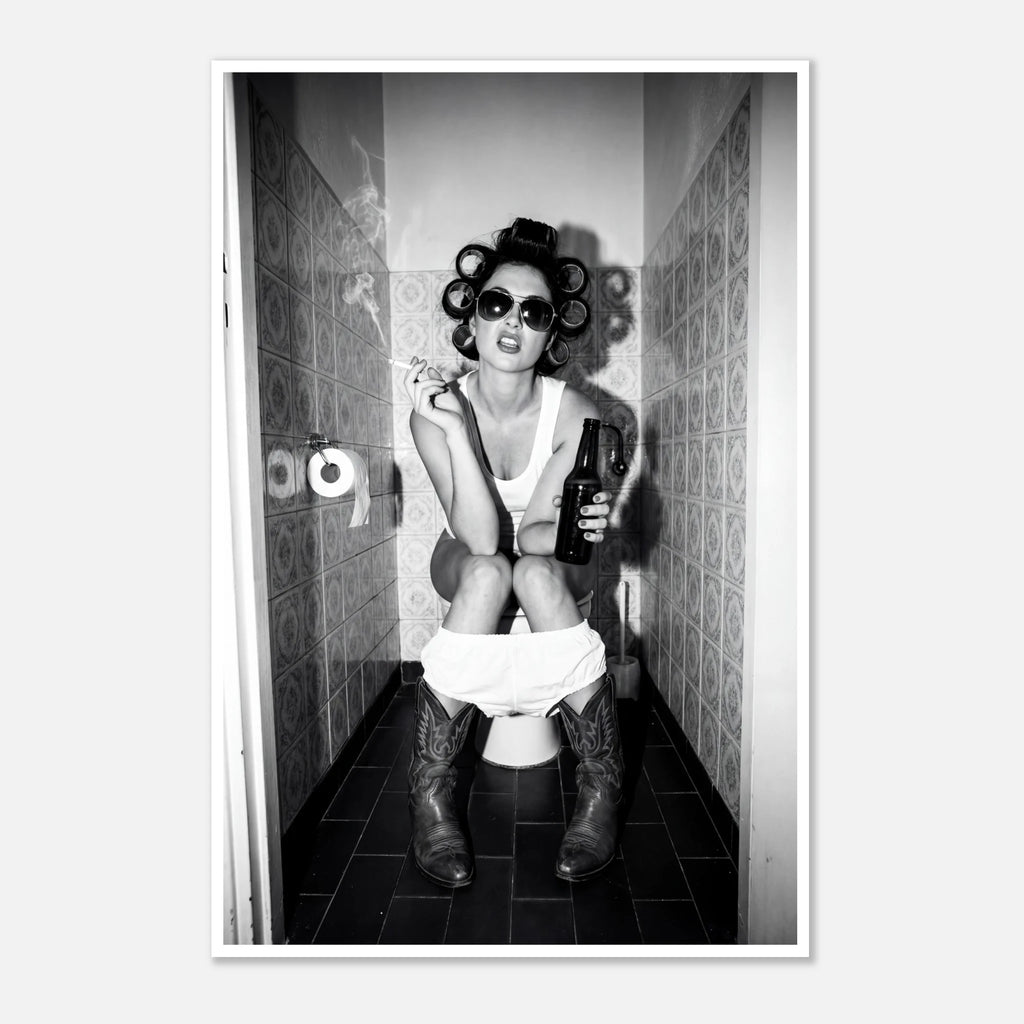 Black and white photograph of a rebellious cowgirl wearing cowboy boots and sunglasses sitting in a tiled restroom holding a cigarette and beer.