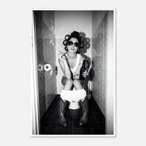 Black and white photograph of a rebellious cowgirl wearing cowboy boots and sunglasses sitting in a tiled restroom holding a cigarette and beer.