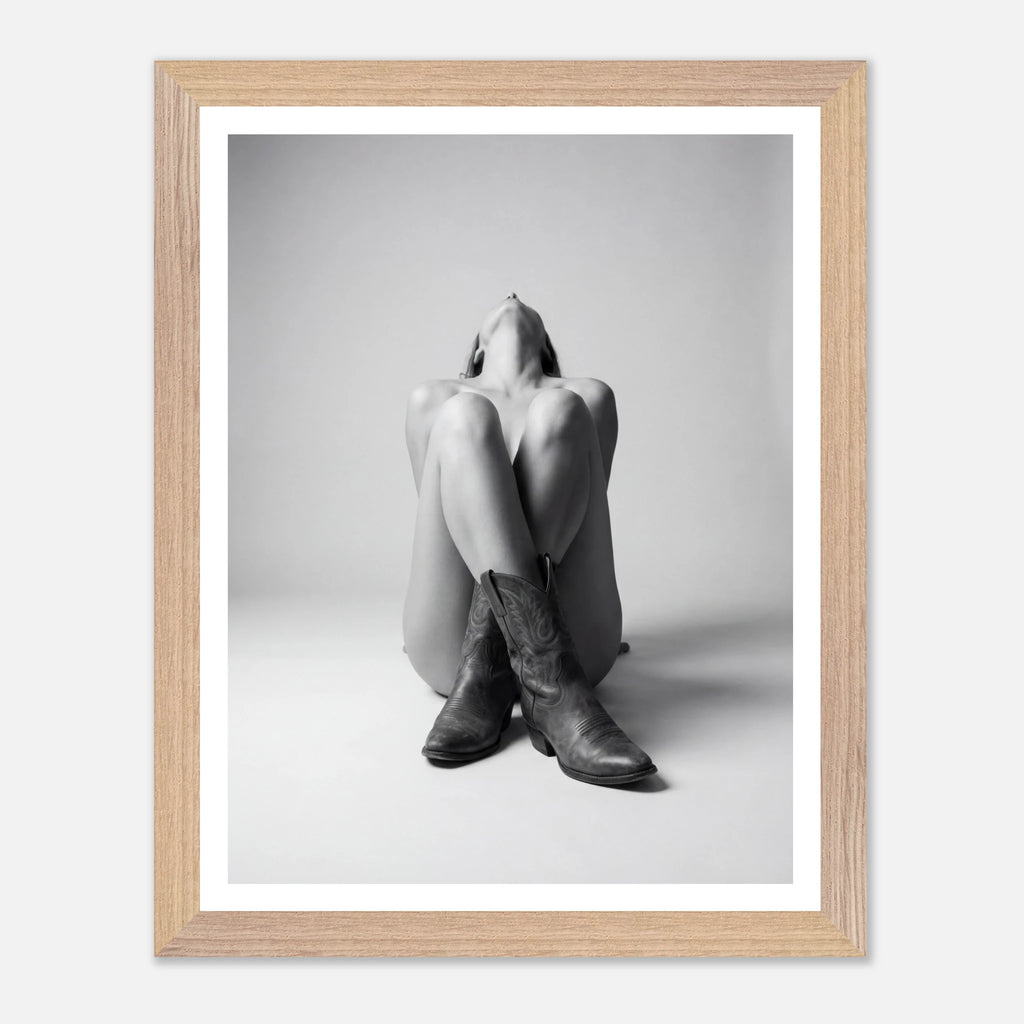 Framed black and white photo of a person wearing cowboy boots on a light gray background