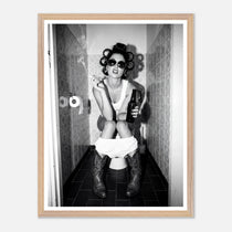 Black and white photograph of a rebellious cowgirl wearing cowboy boots and sunglasses sitting in a tiled restroom holding a cigarette and beer.