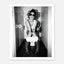 Black and white photograph of a rebellious cowgirl wearing cowboy boots and sunglasses sitting in a tiled restroom holding a cigarette and beer.