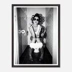Black and white photograph of a rebellious cowgirl wearing cowboy boots and sunglasses sitting in a tiled restroom holding a cigarette and beer.