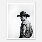 Black and white photograph of a rodeo cowboy wearing a western hat and cigarette, turning toward the camera after competition, western cowboy wall art poster.