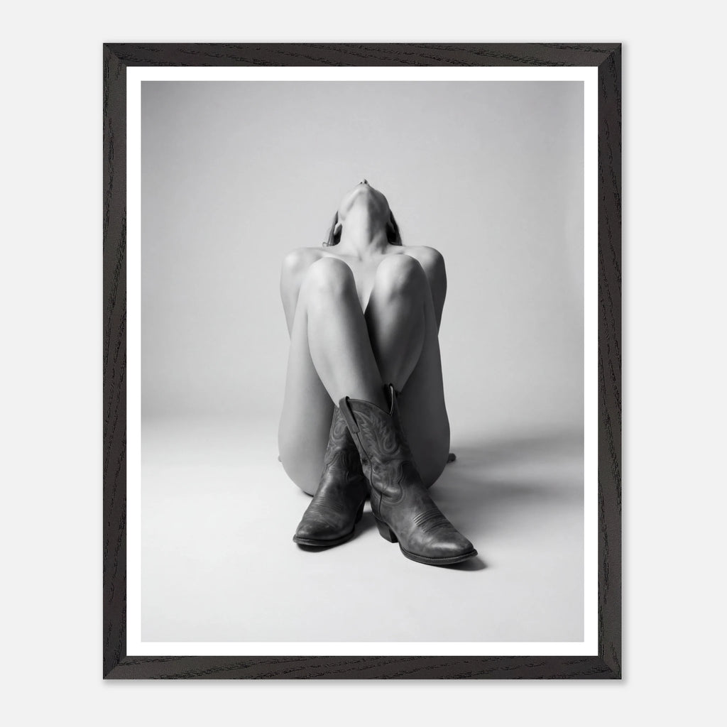 Framed black and white art print of a person sitting with legs crossed wearing cowboy boots.