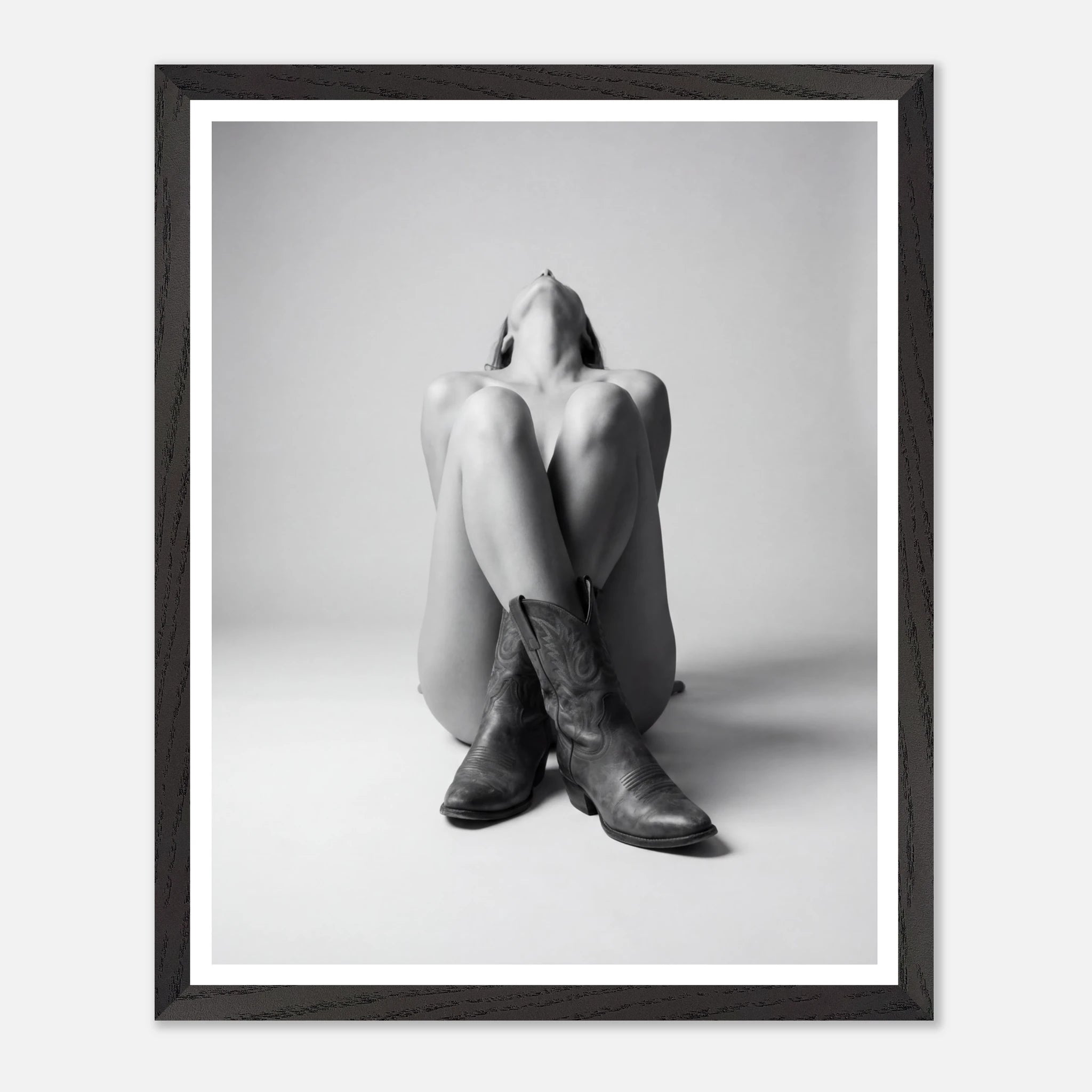 Framed black and white art print of a person sitting with legs crossed wearing cowboy boots.