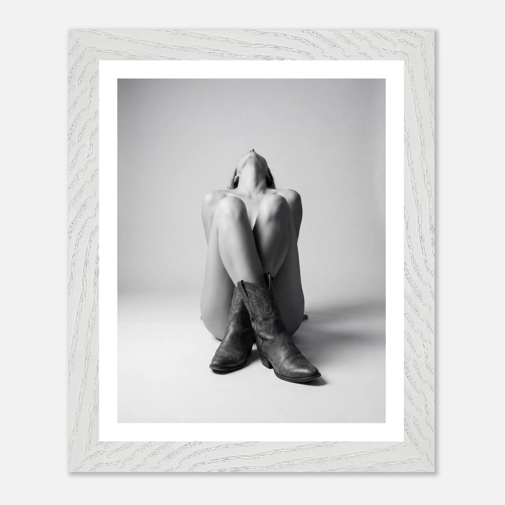 Framed black and white photo of a person wearing cowboy boots sitting on the floor.
