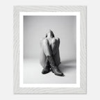Framed black and white photo of a person wearing cowboy boots sitting on the floor.