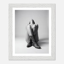 Framed black and white photo of a person wearing cowboy boots sitting on the floor.