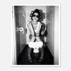 Black and white photograph of a rebellious cowgirl wearing cowboy boots and sunglasses sitting in a tiled restroom holding a cigarette and beer.