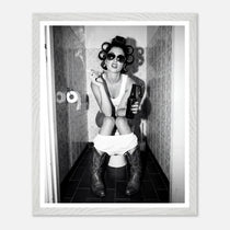 Black and white photograph of a rebellious cowgirl wearing cowboy boots and sunglasses sitting in a tiled restroom holding a cigarette and beer.