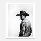 Black and white photograph of a rodeo cowboy wearing a western hat and cigarette, turning toward the camera after competition, western cowboy wall art poster.