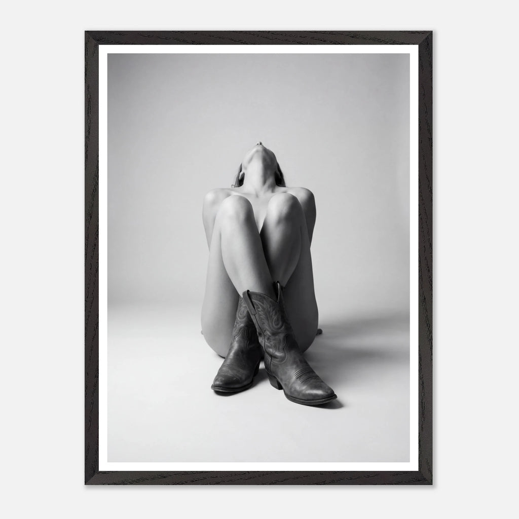 Framed black and white art print of a person wearing cowboy boots sitting on the floor.