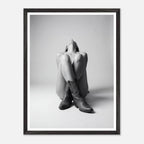 Framed black and white art print of a person wearing cowboy boots sitting on the floor.