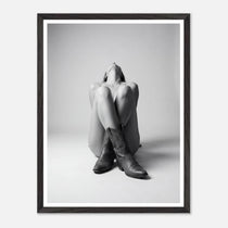Framed black and white art print of a person wearing cowboy boots sitting on the floor.