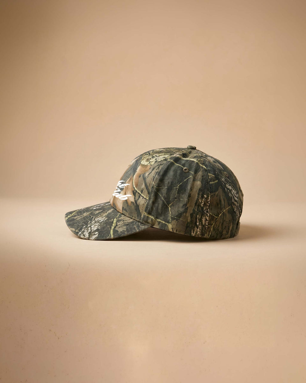 Camouflage baseball cap with 'Midnight Rodeo Club' text on a beige background