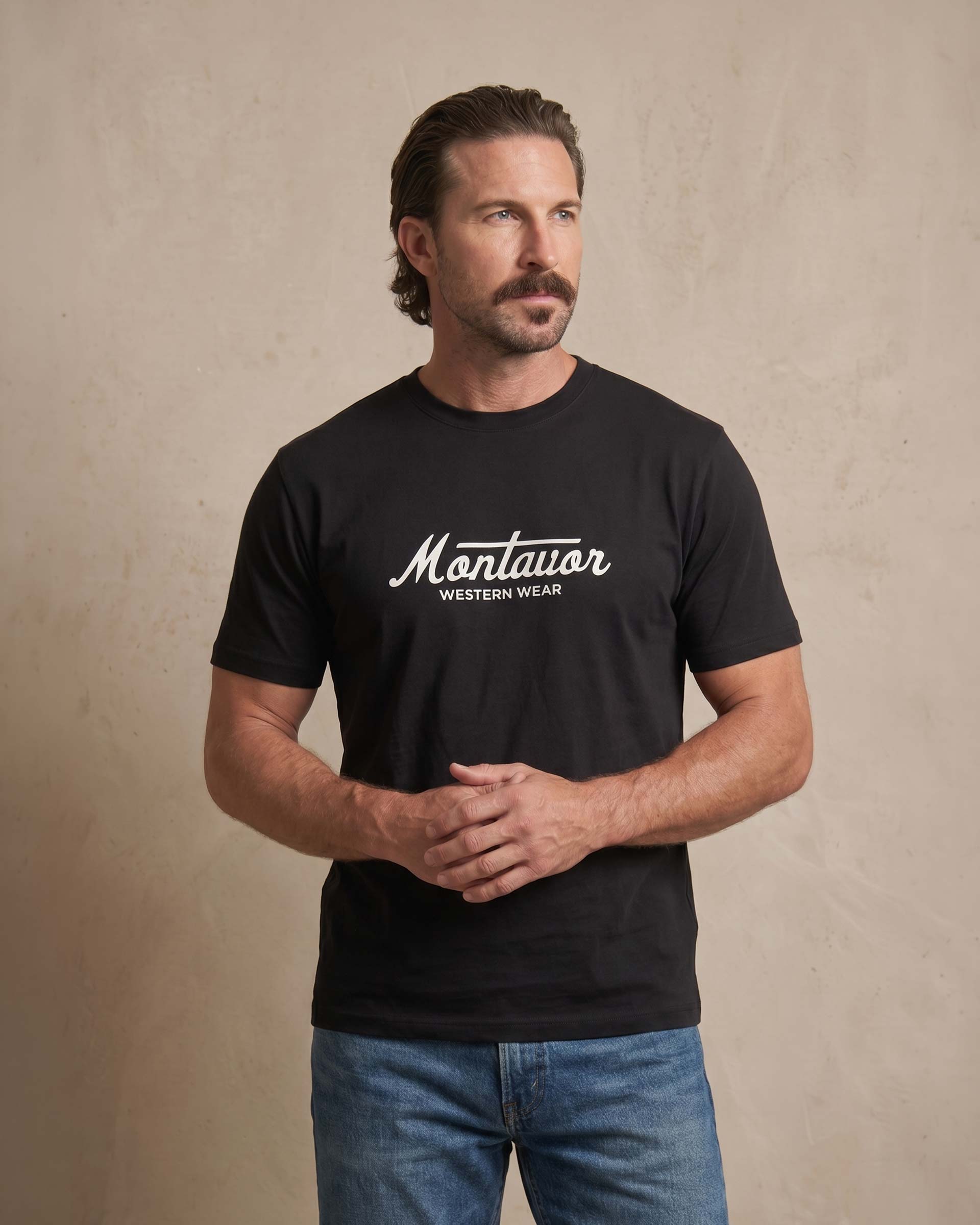 Man wearing a black t-shirt with 'Montavor Western Wear' logo against a beige background