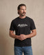 Man wearing a black t-shirt with 'Montavor Western Wear' logo against a beige background