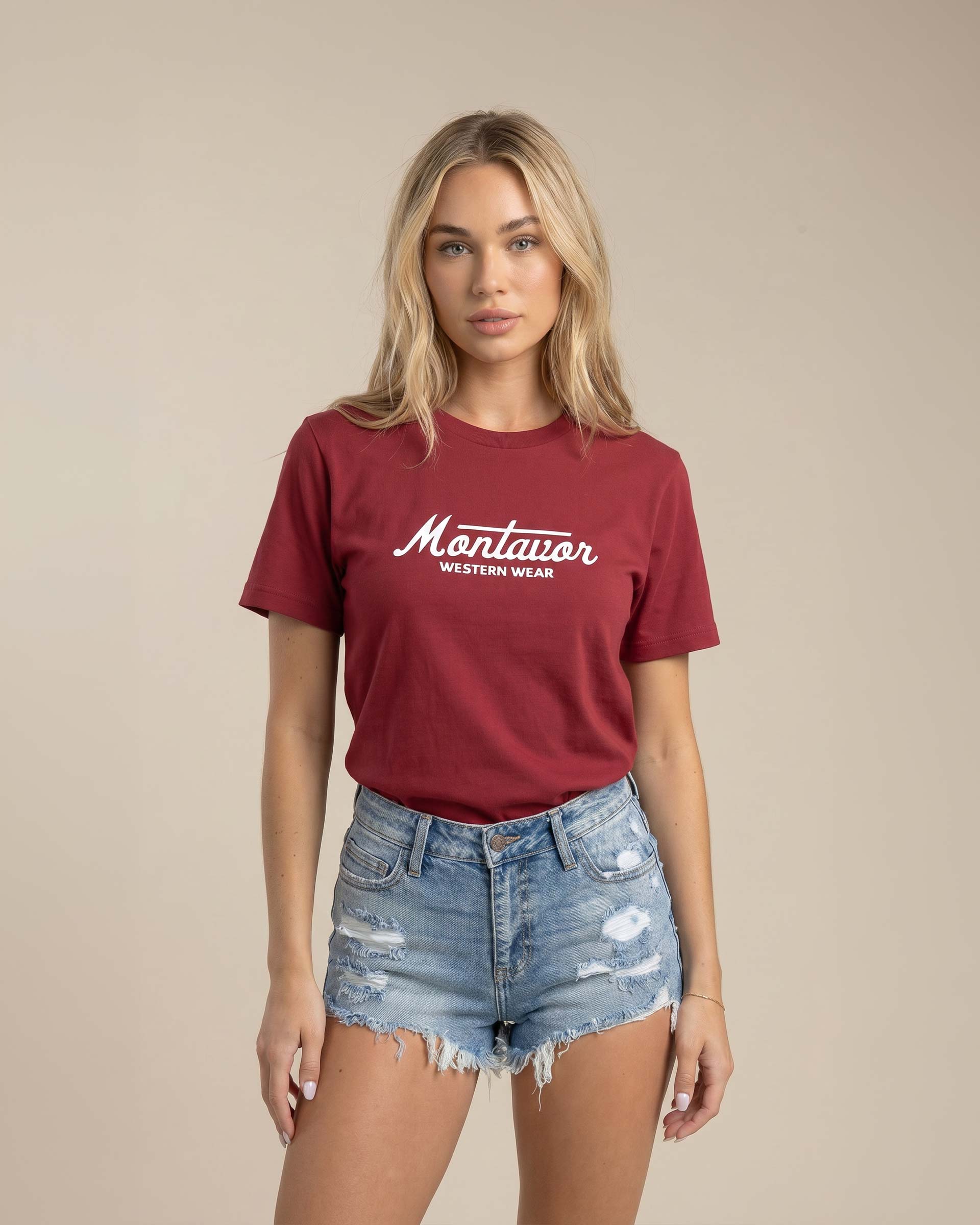 Woman wearing a maroon t-shirt with 'Montavor' logo and denim shorts on a beige background Main image