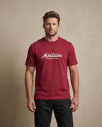 Man wearing a red t-shirt with 'Montavor Western Wear' logo against a beige background