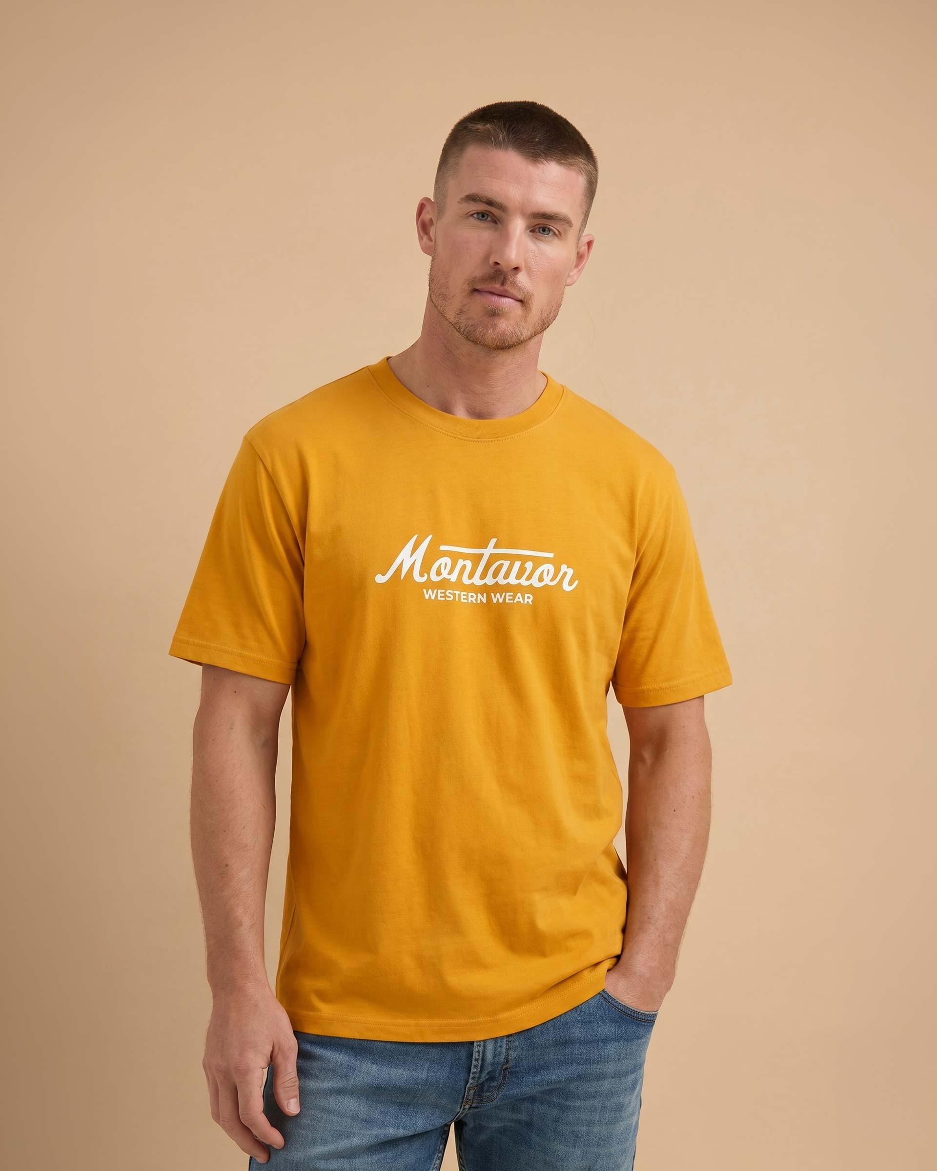 Man wearing a mustard yellow t-shirt with 'Montavor Western Wear' logo on a beige background